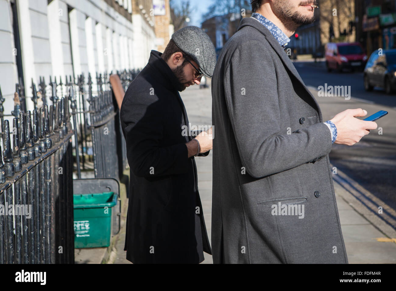 Hipsters using phones on London Street Stock Photo