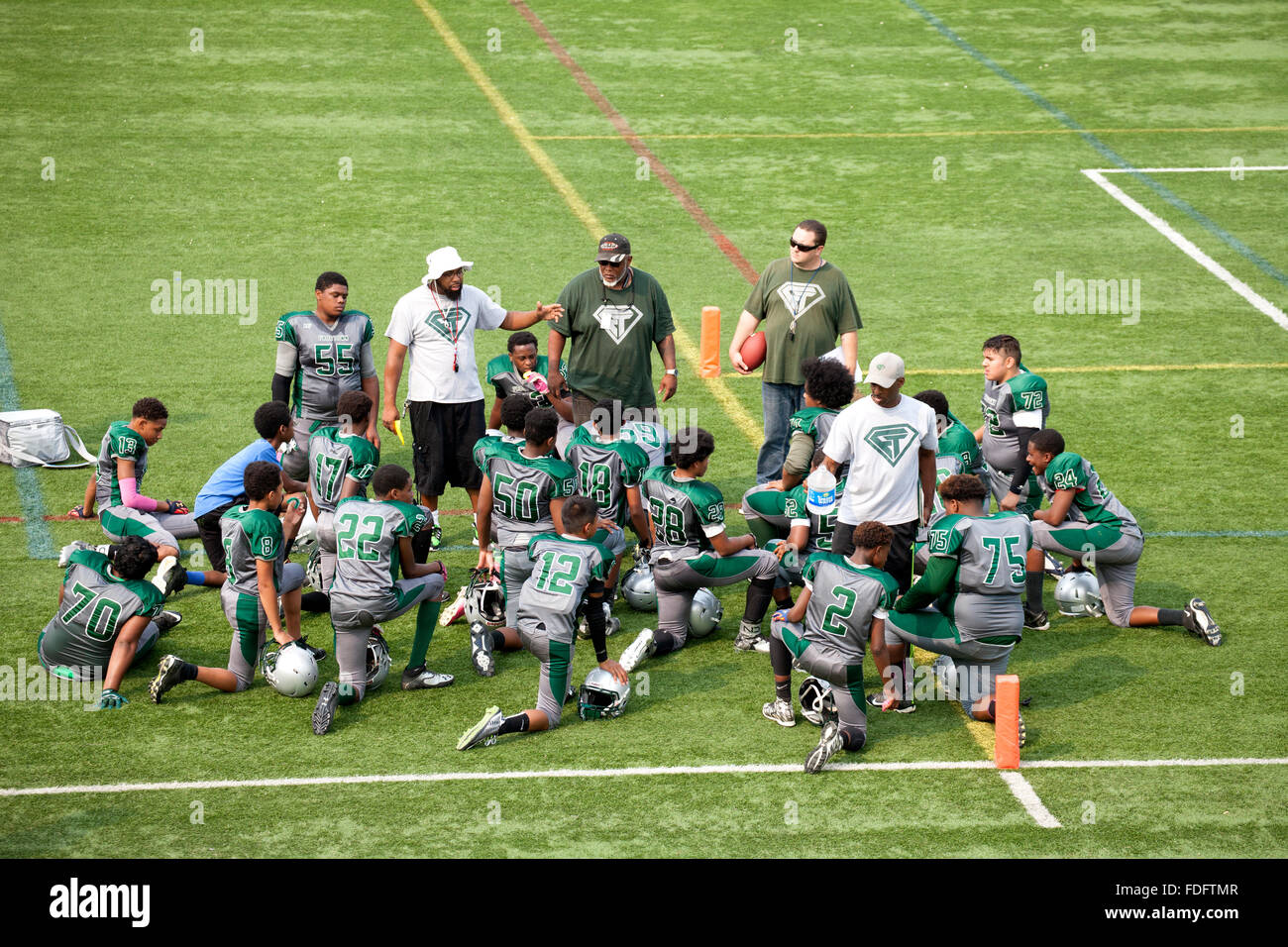 Black coach instructing his black boys football team age 12 on the field. St Paul Minnesota MN USA Stock Photo