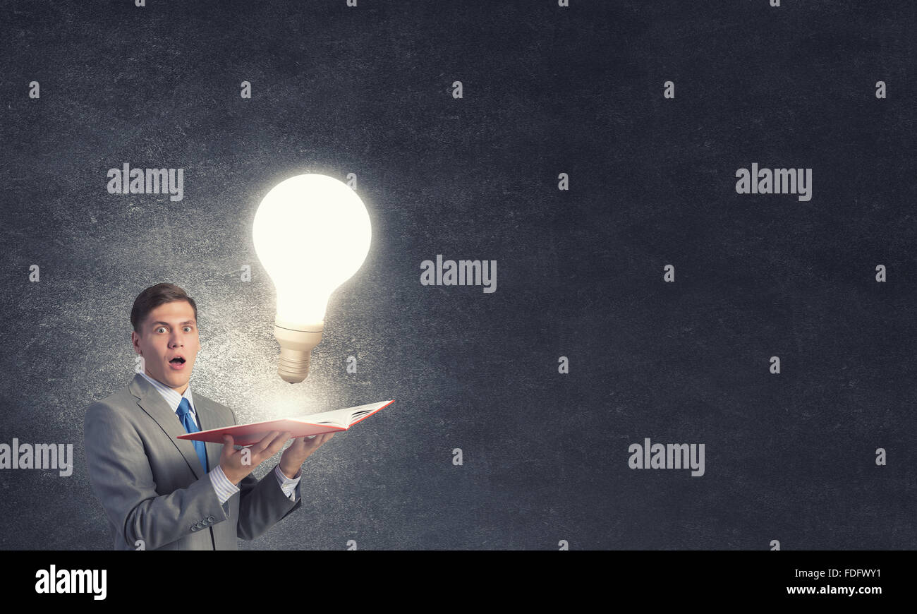 Businessman holding opened book with glass glowing light bulb Stock ...
