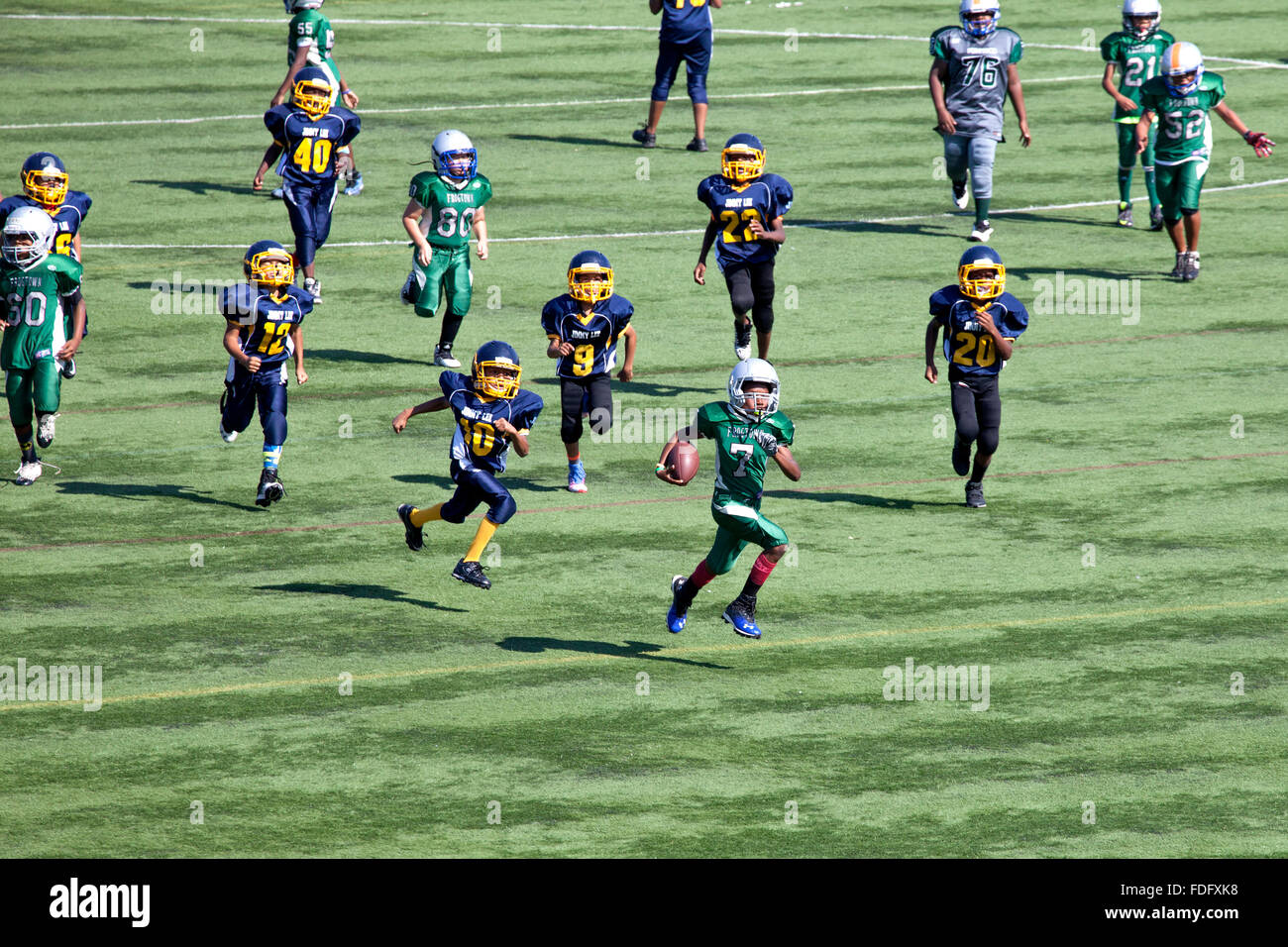 Black boy age 11 runs away from opposing players with football. McMurray Field St Paul Minnesota MN USA Stock Photo