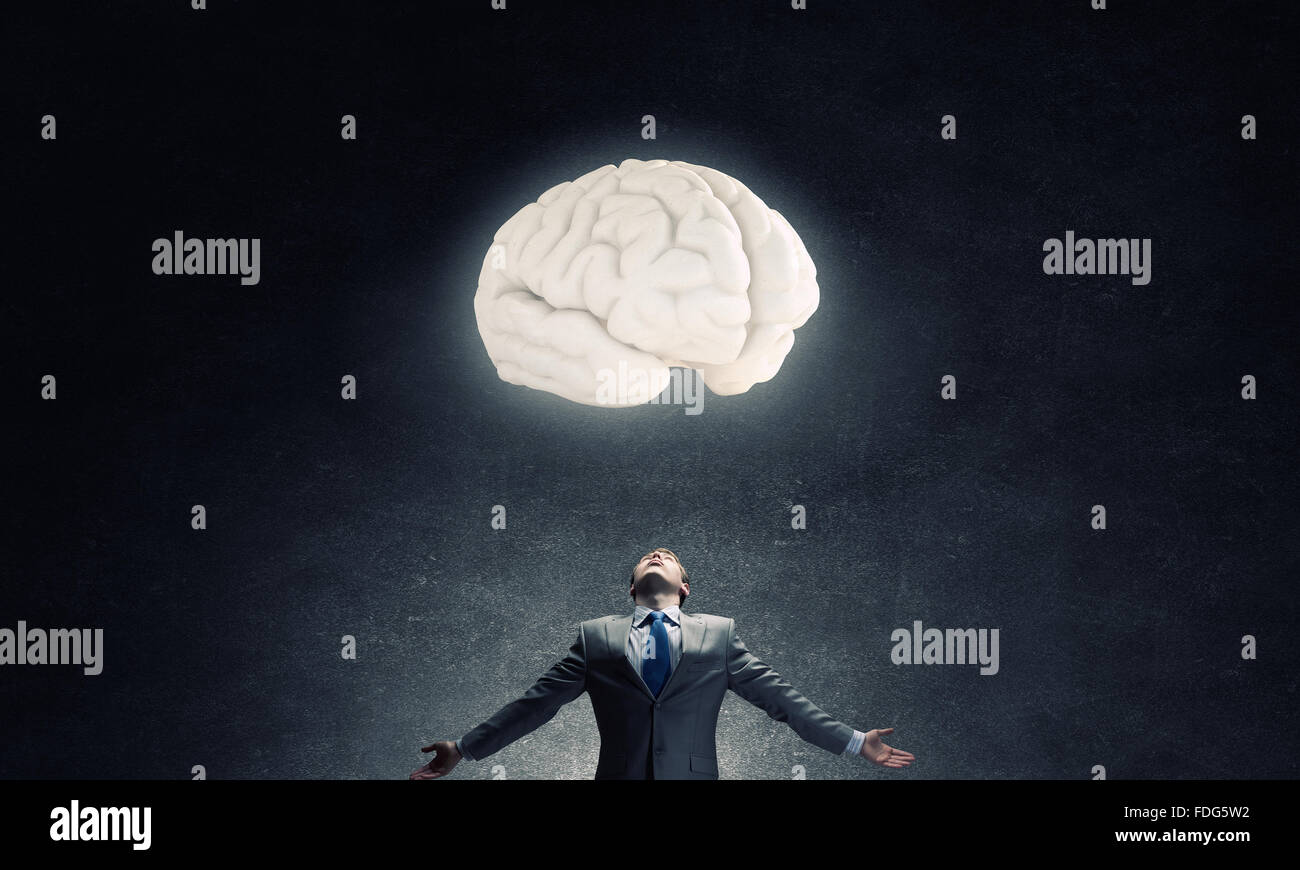 Businessman with hands spread wide and human brain above his head Stock Photo