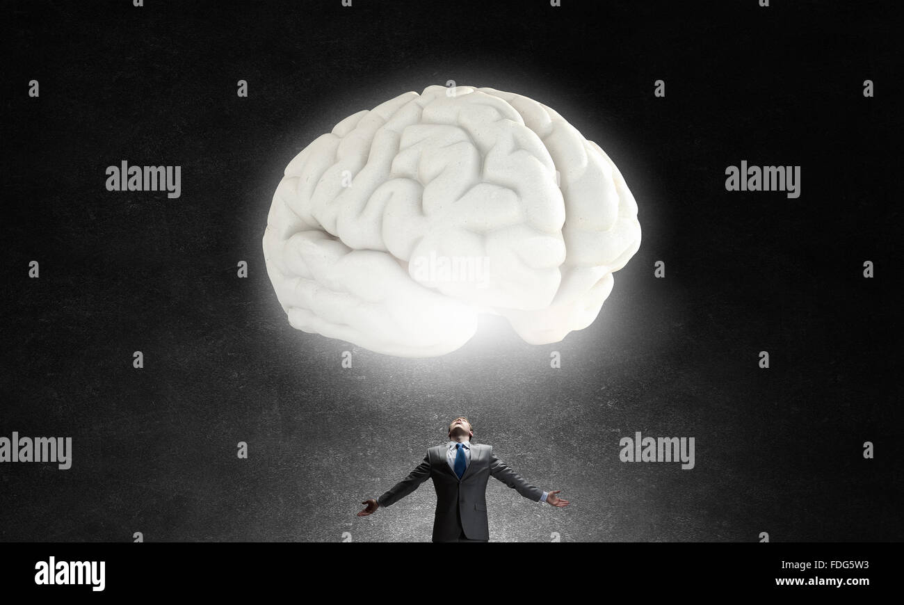 Businessman with hands spread wide and human brain above his head Stock Photo
