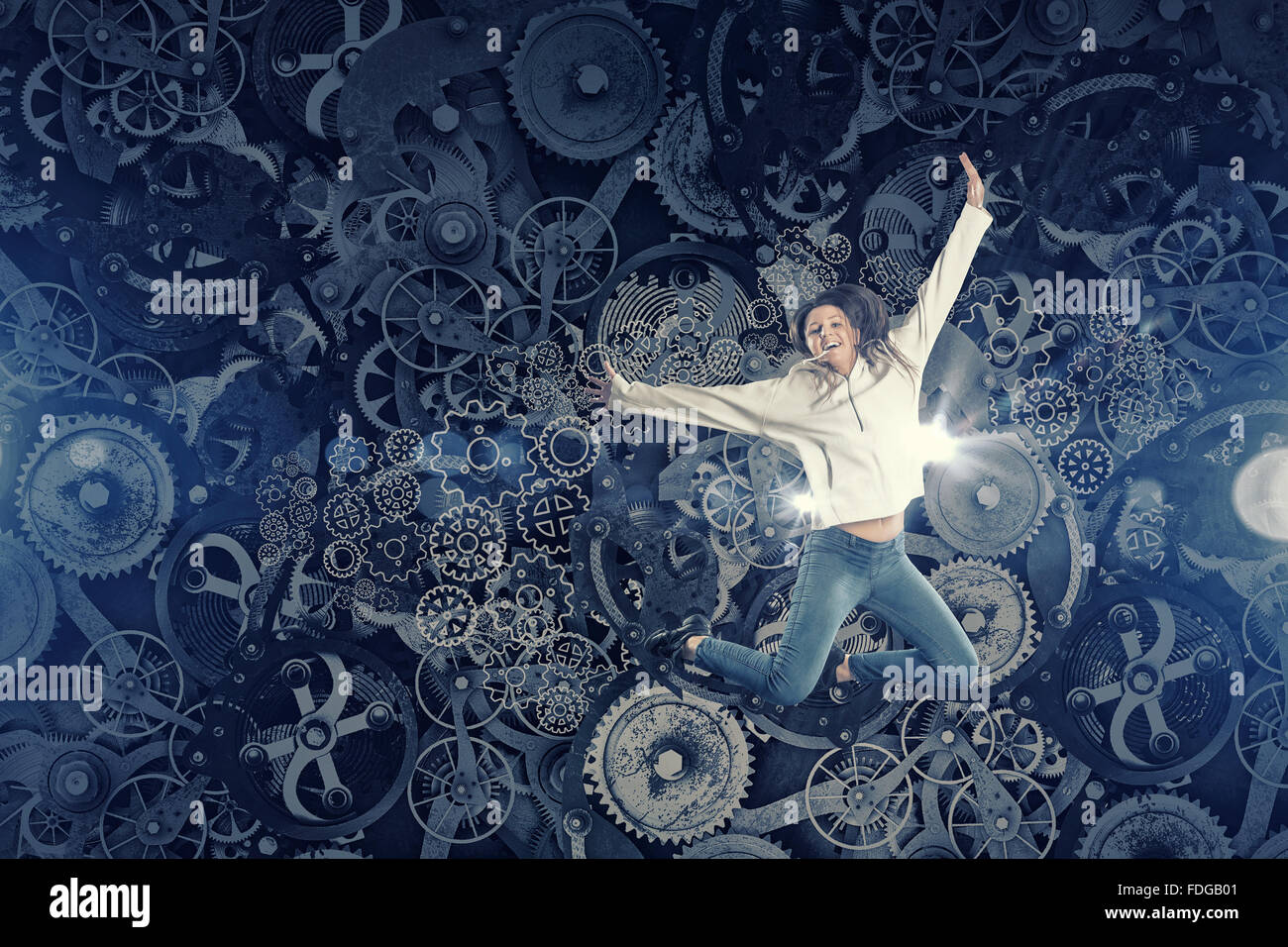 Young woman dancer jumping in spotlights on gears background Stock