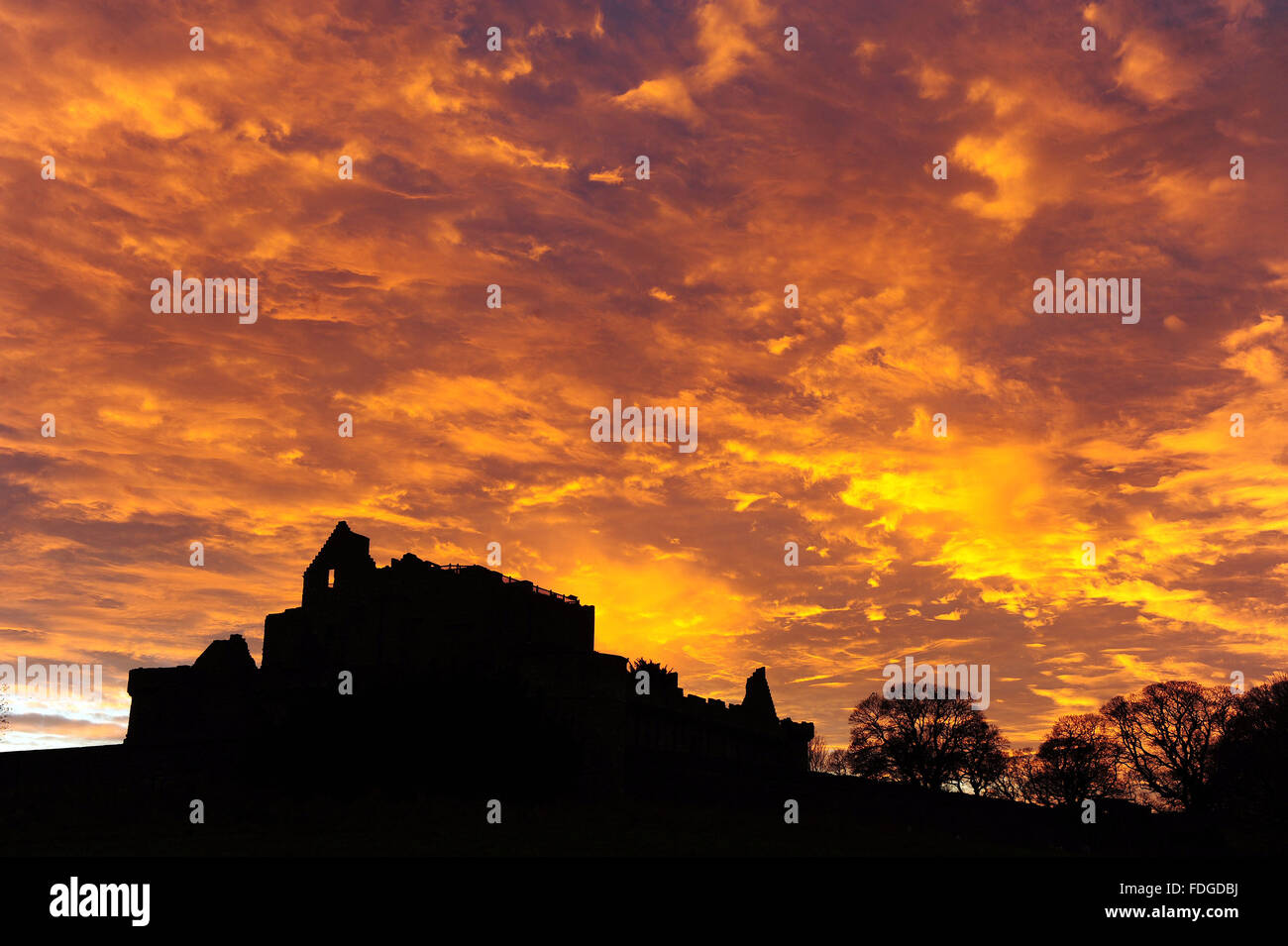 Red sky, Craigmillar Castle, Edinburgh. The phenomenon called Rayleigh scattering: cirrus clouds scatter the longer, red wavelengths of light. Stock Photo