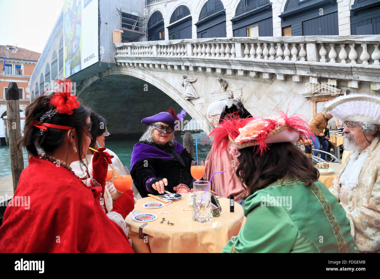 Carnevale di Venezia -  Venice Carnival 2016 - Tourists in costumes taking a spritz break at Rialto Bridge. Stock Photo
