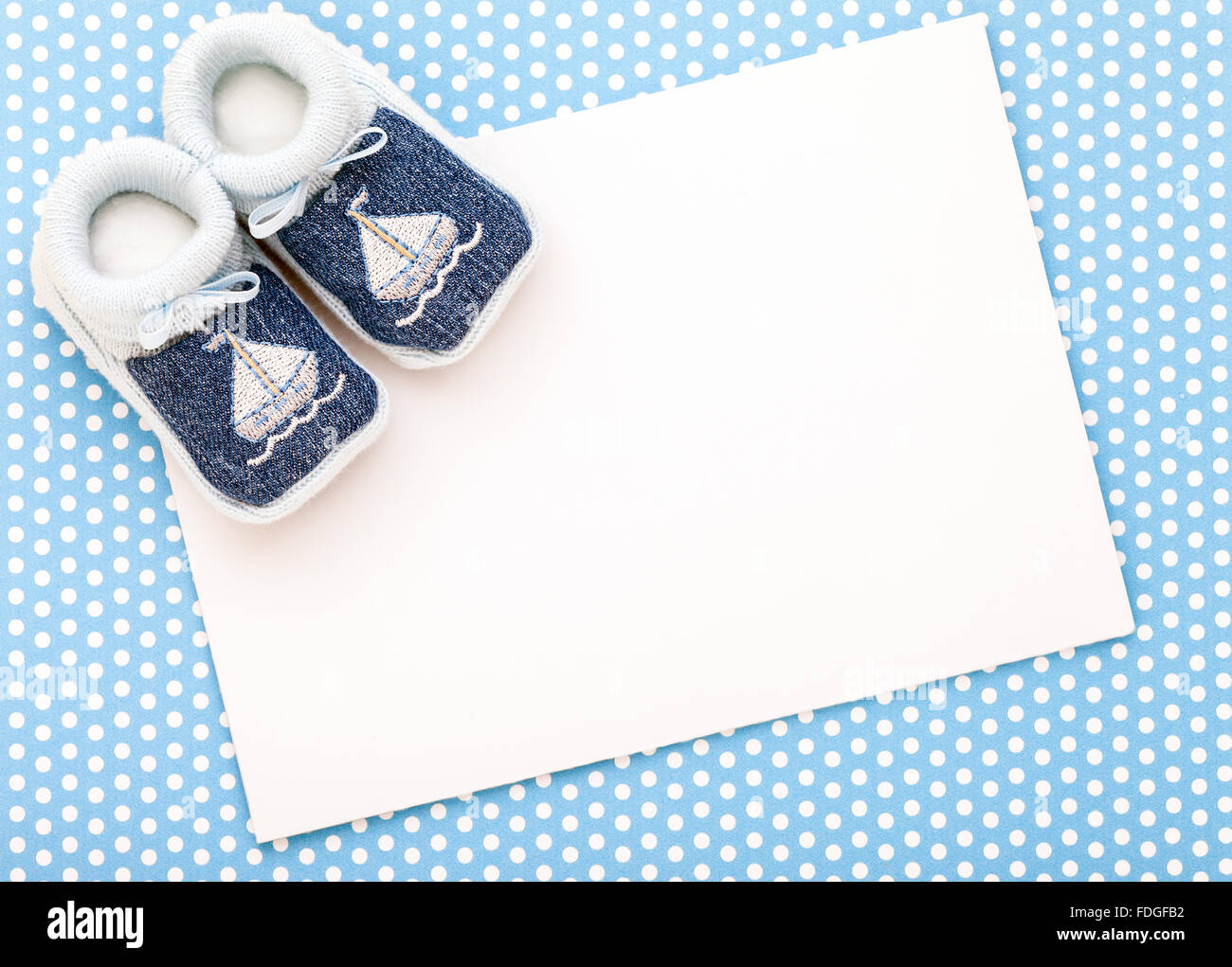 Announcement invitation card with baby shoes on polka dot background. Stock Photo