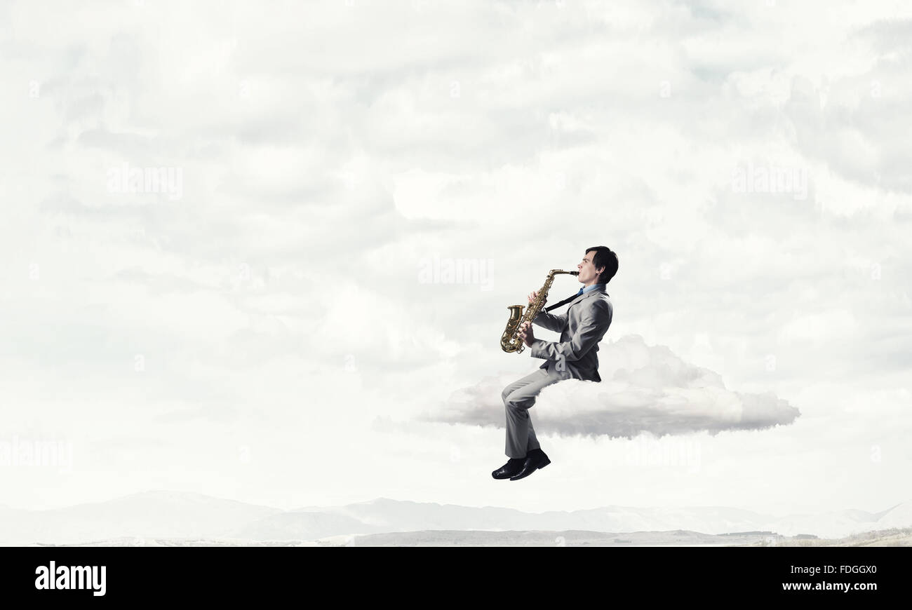 Young man sitting on cloud playing saxophone Stock Photo Alamy