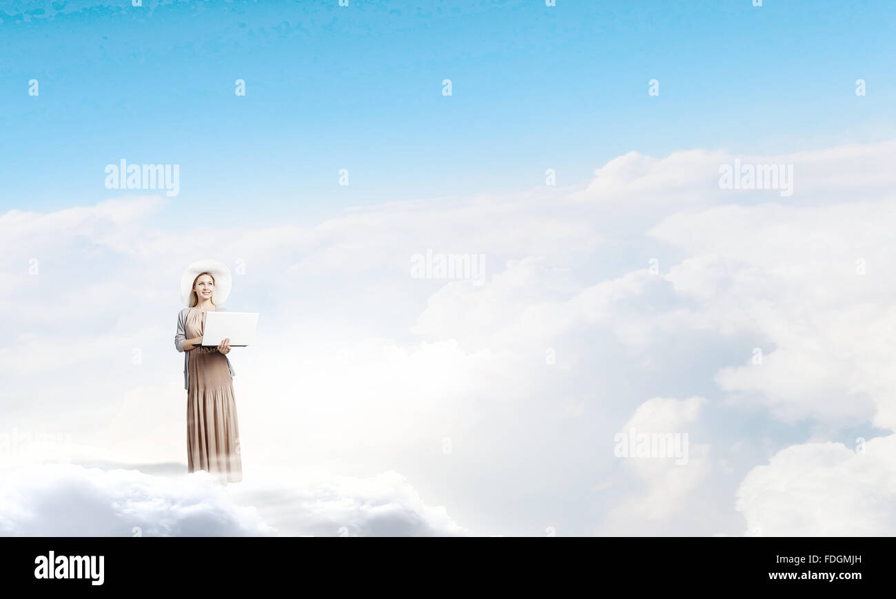 Young lady standing on cloud and using laptop Stock Photo - Alamy