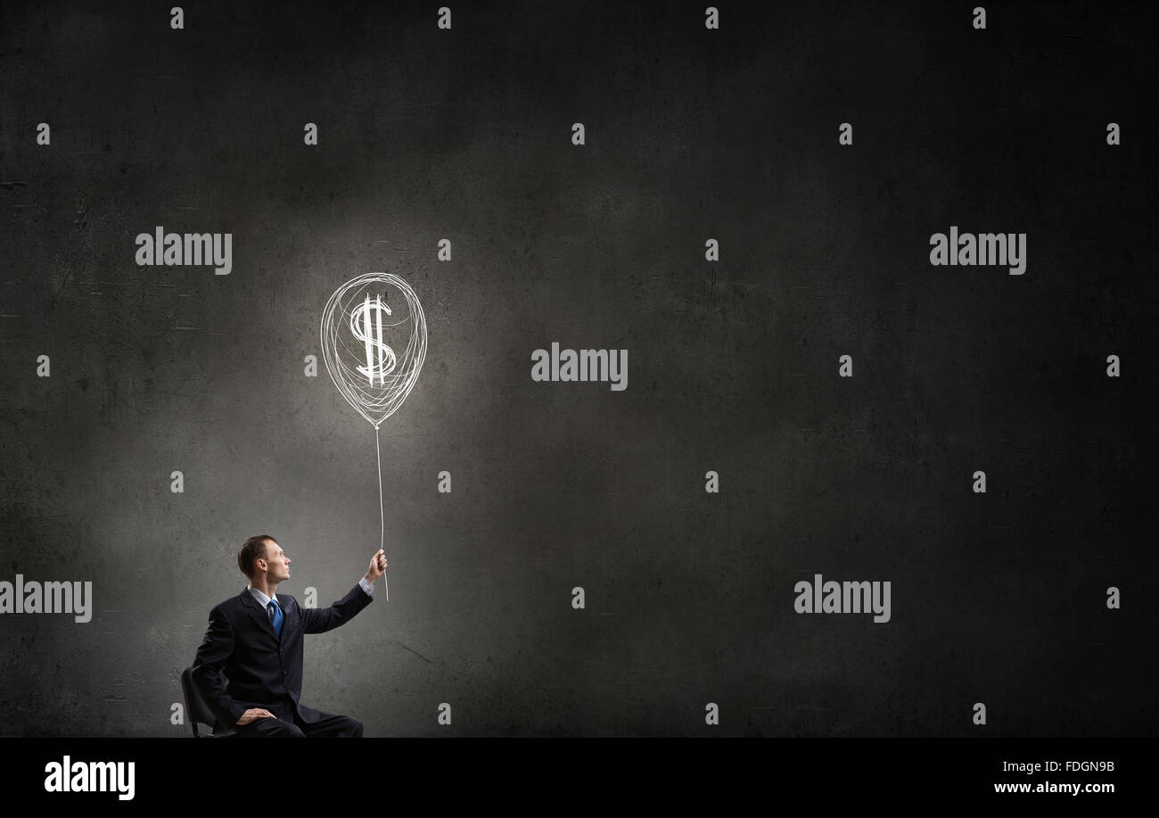 Businessman in chair holding dollar sign balloon Stock Photo - Alamy