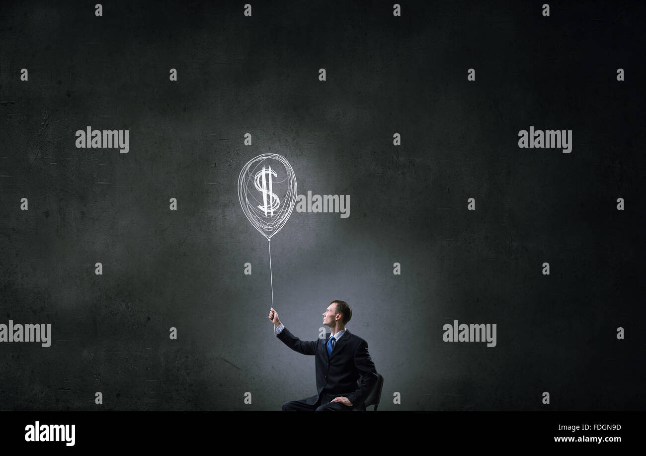 Businessman in chair holding dollar sign balloon hi-res stock ...