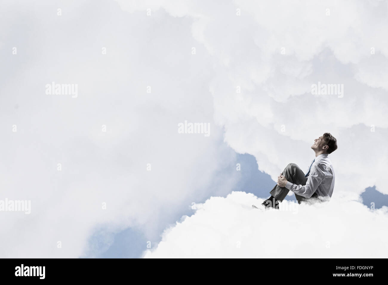 Smiling young businessman sitting alone on cloud high in sky Stock ...