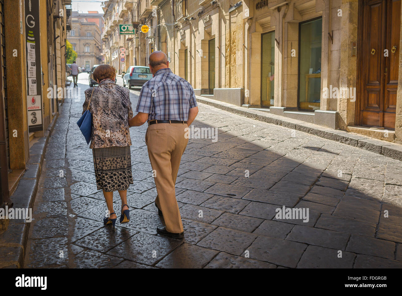 Senior couple walking, rear view of an elderly couple making their way up to the Piazza Umberto in Enna, Sicily, to begin the evening passeggiata. Stock Photo