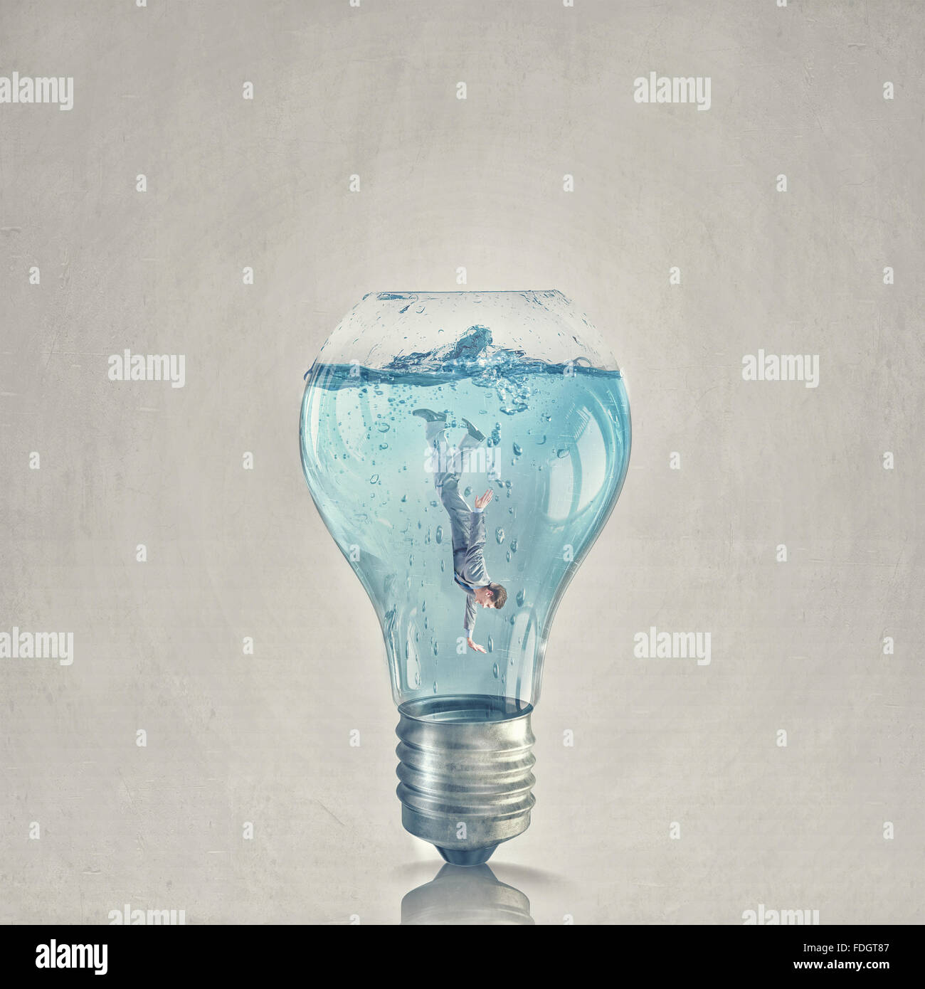 Glass light bulb filled with clear water and businessman inside Stock