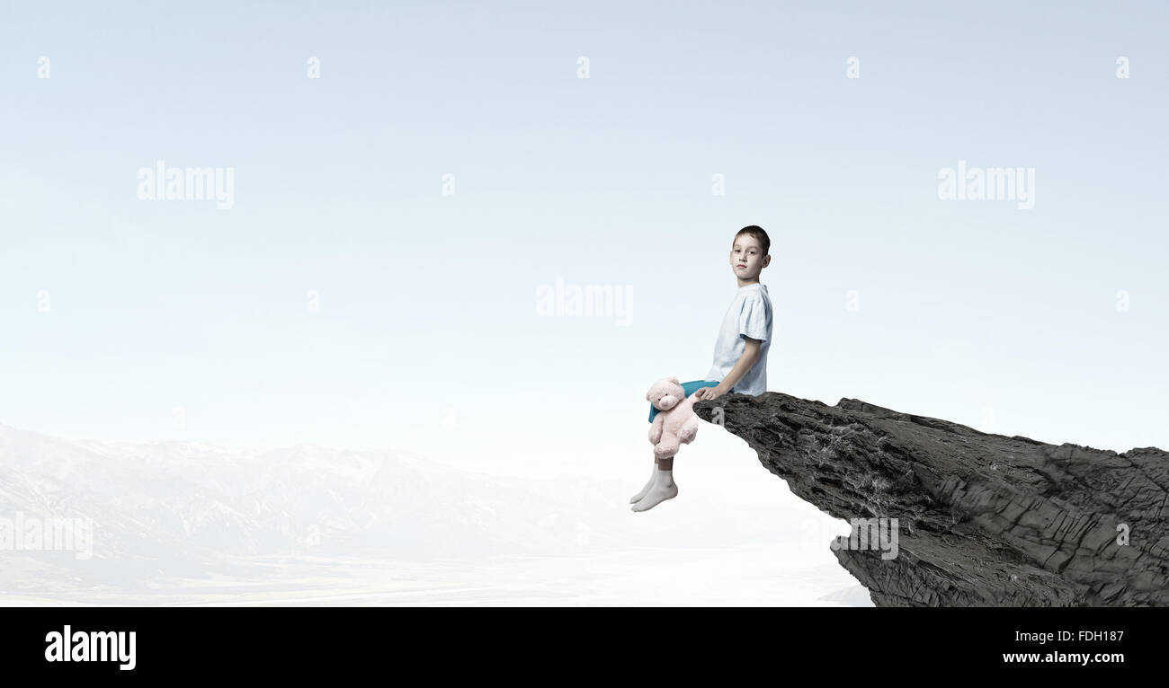 Cute little boy with toy bear on rock top Stock Photo - Alamy