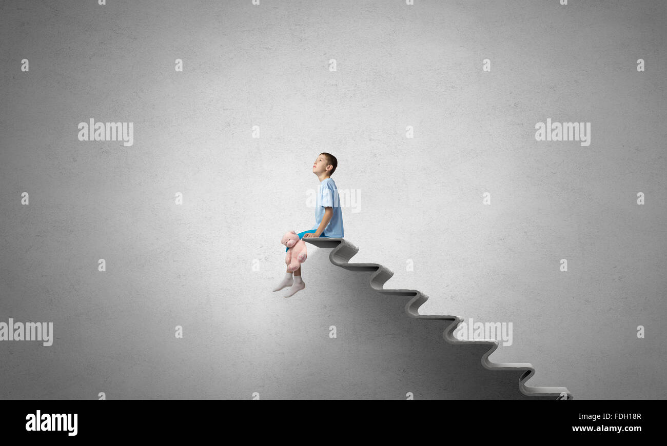 Cute little boy with toy bear sitting on ladder of books Stock Photo ...