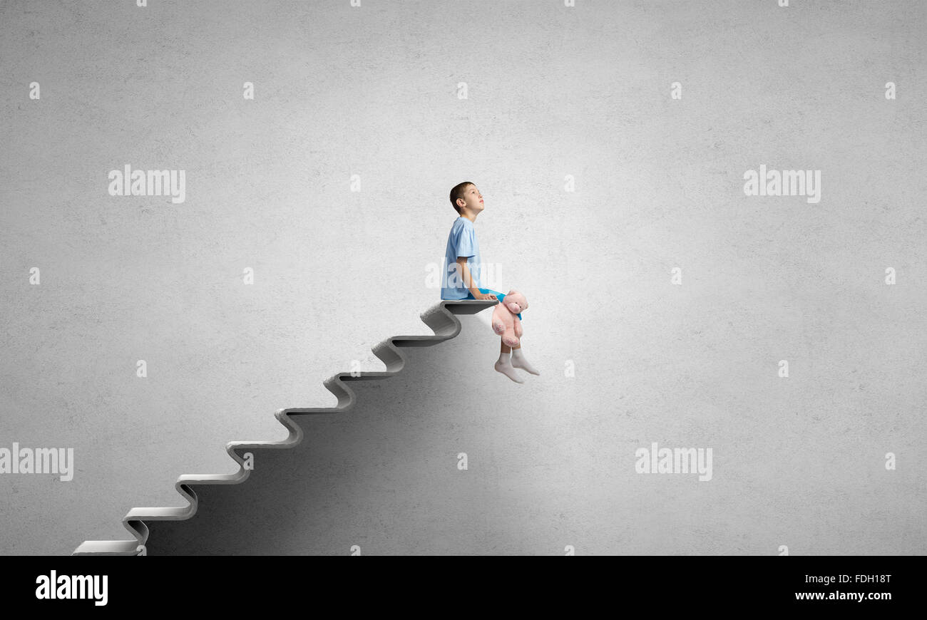 Cute little boy with toy bear sitting on ladder of books Stock Photo ...