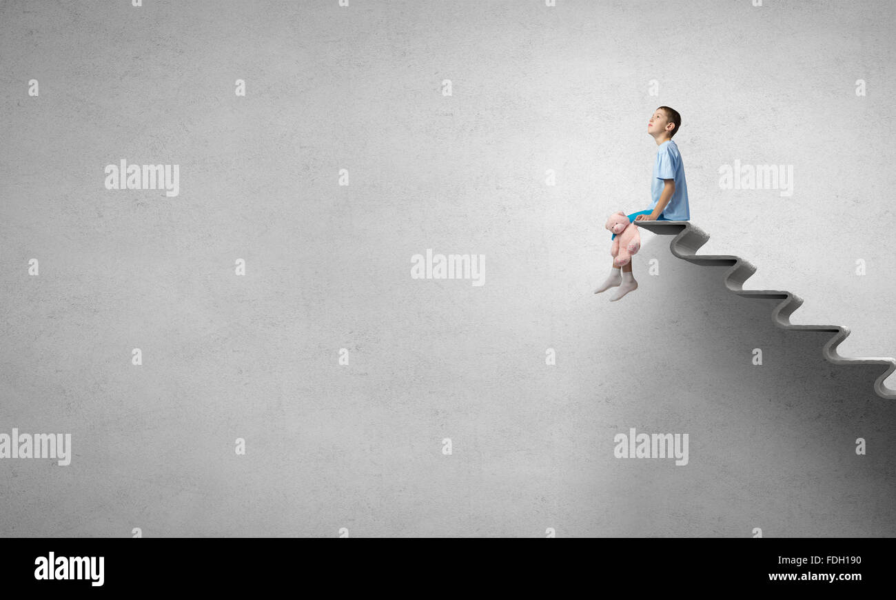 Cute little boy with toy bear sitting on ladder of books Stock Photo ...