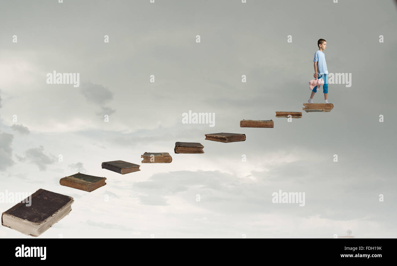 Cute little boy with toy bear walking on ladder of books Stock Photo ...