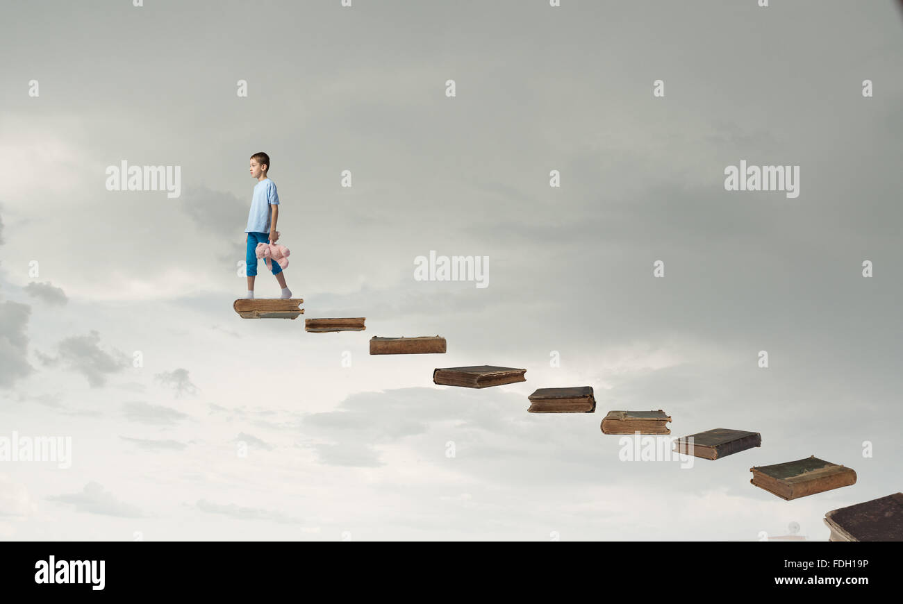 Cute little boy with toy bear walking on ladder of books Stock Photo ...