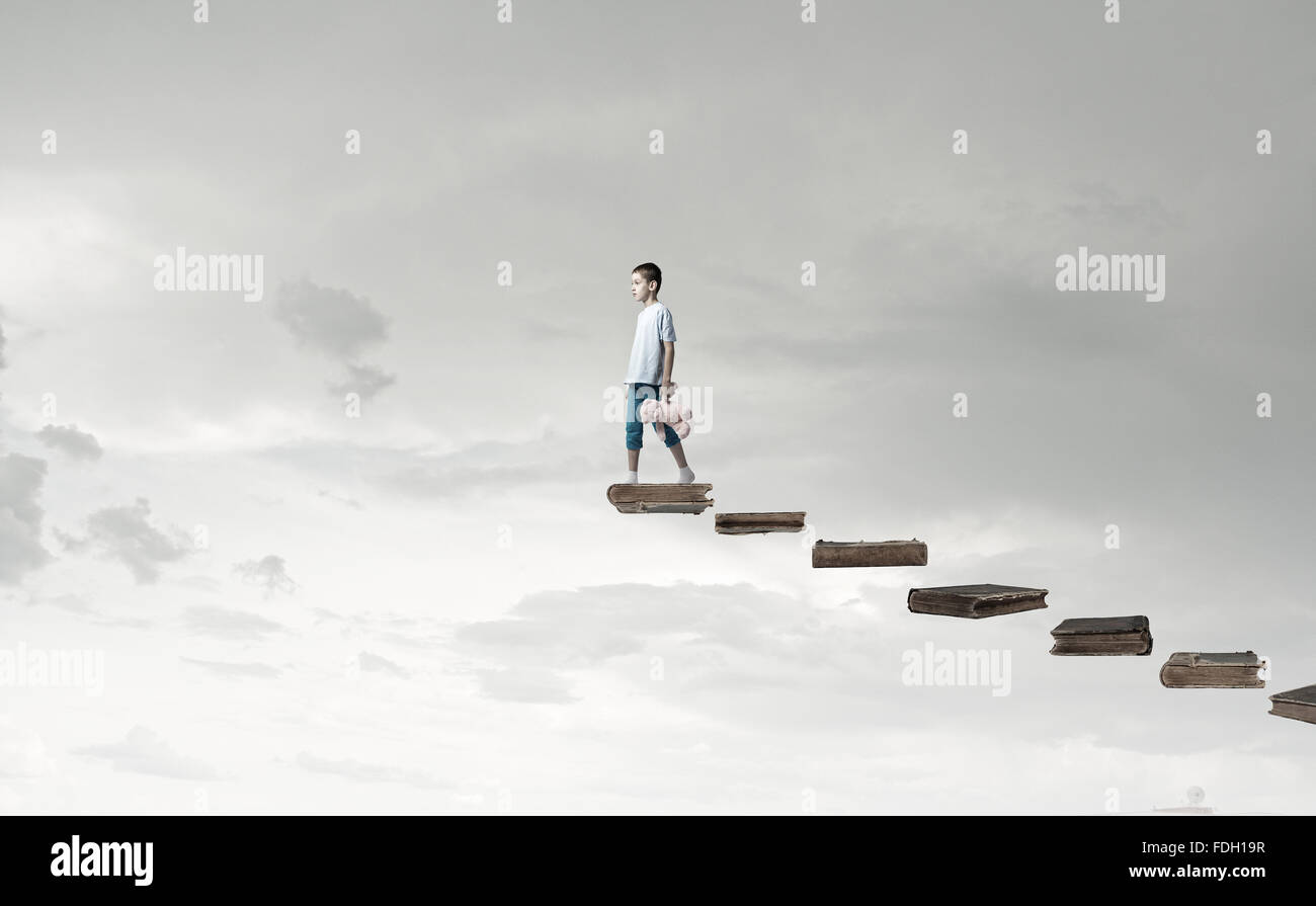 Cute little boy with toy bear walking on ladder of books Stock Photo ...