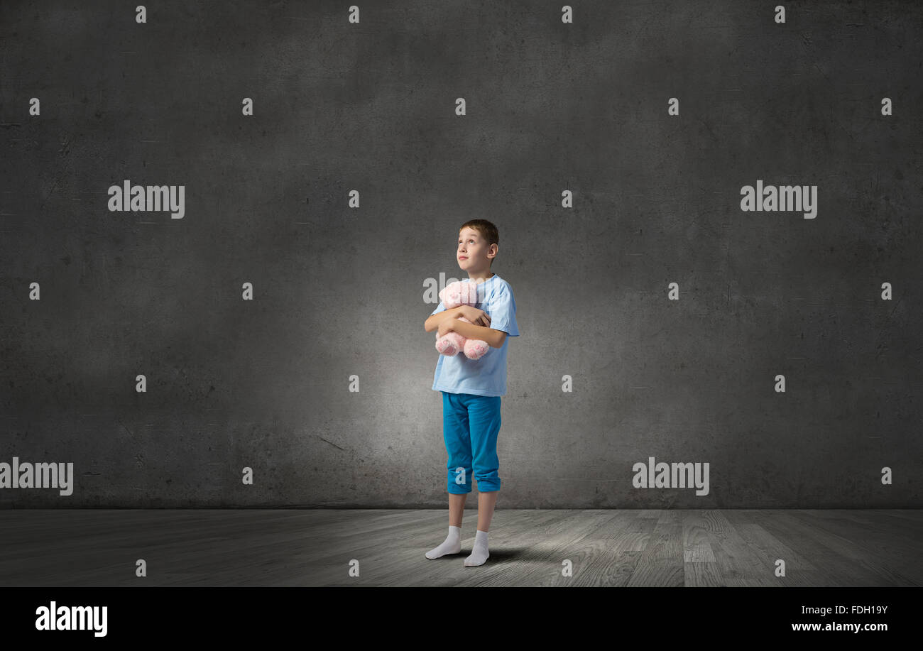 Cute little boy with toy bear in concrete dark room Stock Photo - Alamy