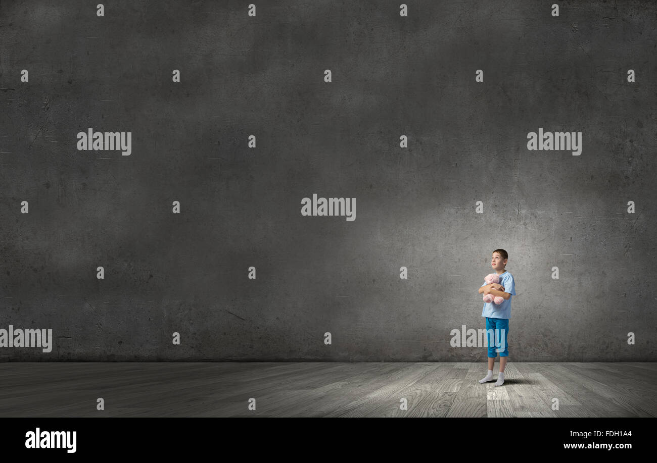 Cute little boy with toy bear in concrete dark room Stock Photo - Alamy