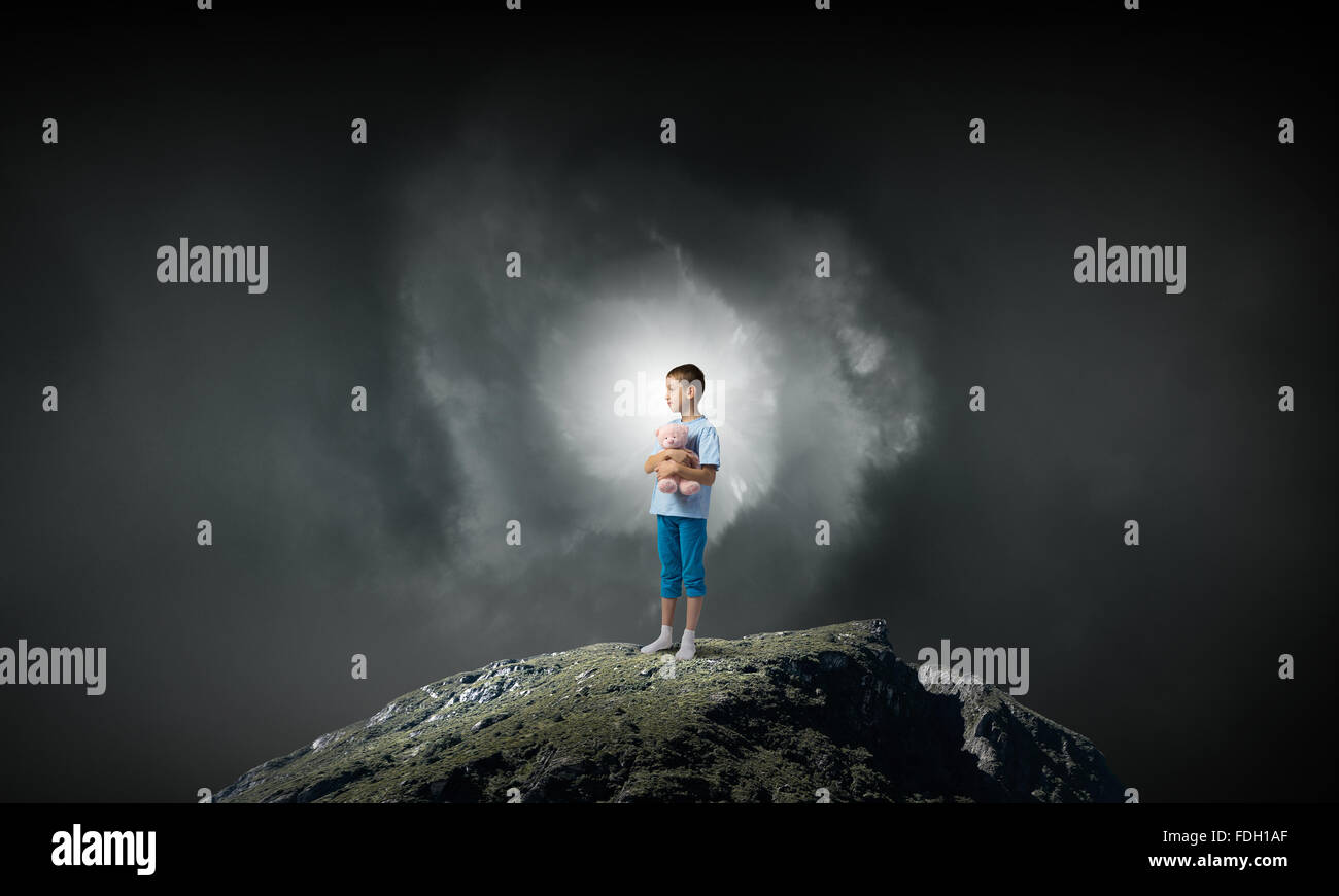 Cute little boy with toy bear on rock top Stock Photo - Alamy