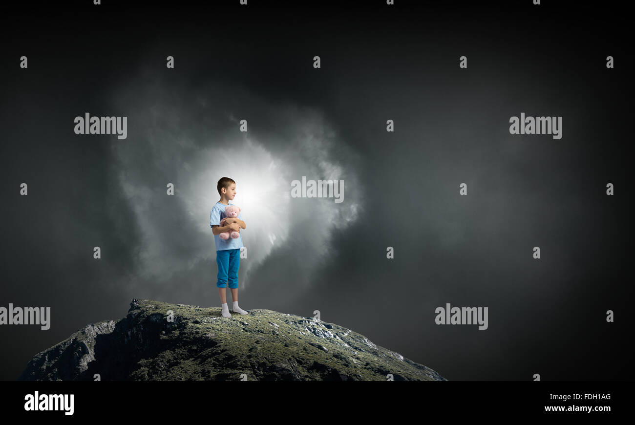 Cute little boy with toy bear on rock top Stock Photo - Alamy