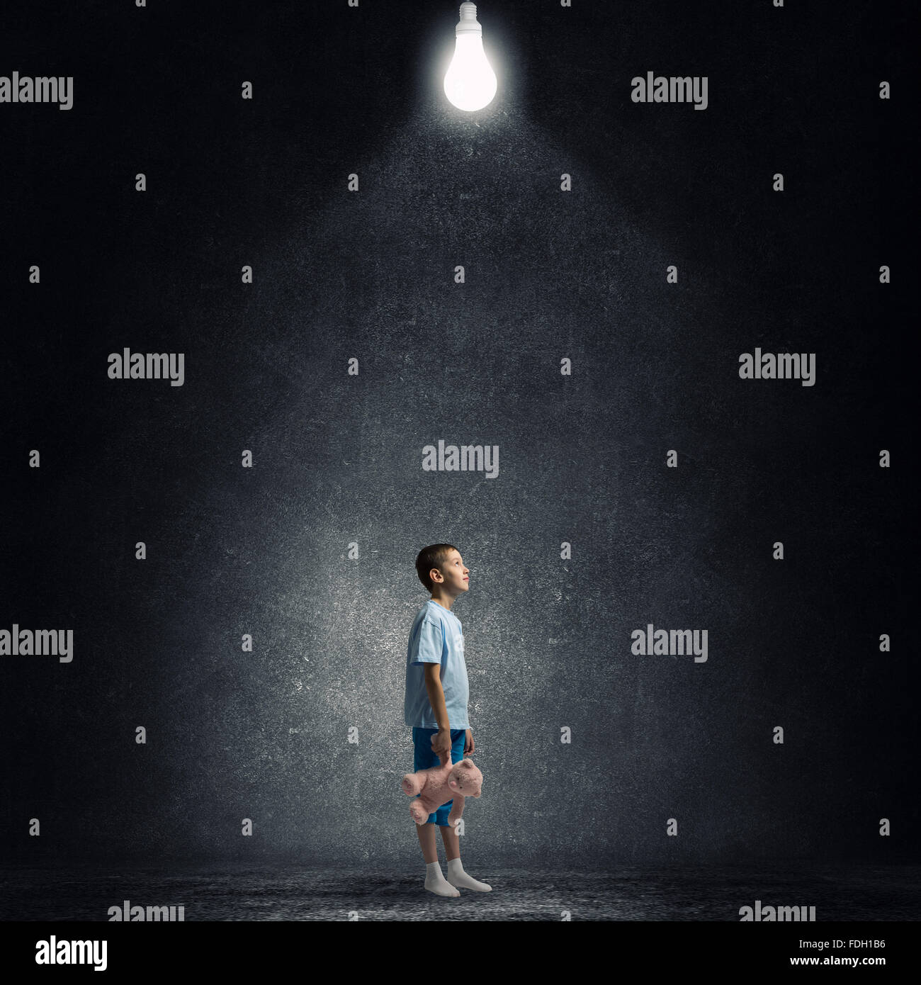 Cute little boy with toy bear in concrete dark room Stock Photo - Alamy