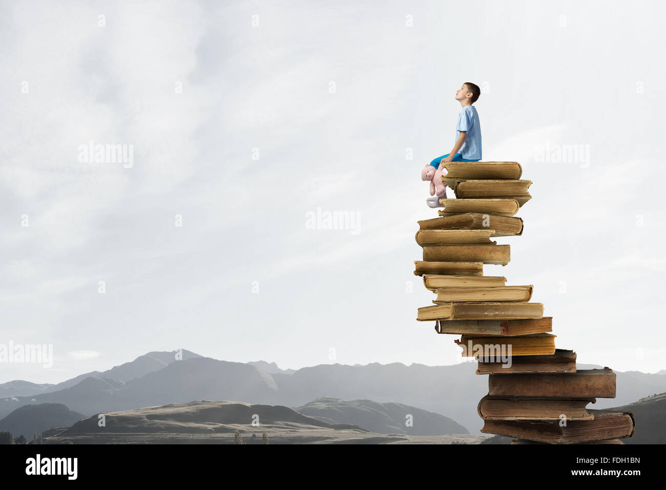 Cute little boy with toy bear sitting on pile of books Stock Photo - Alamy