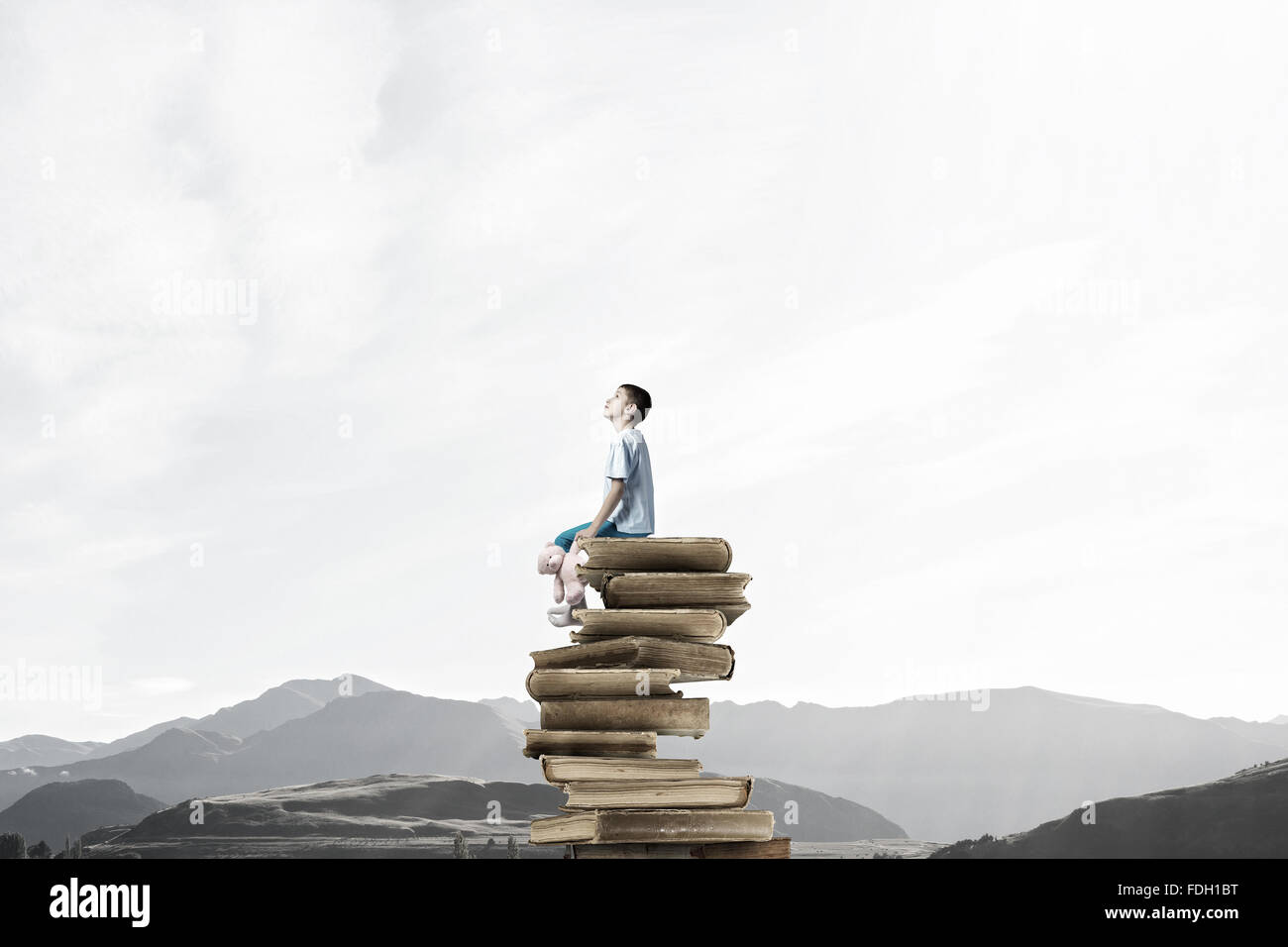 Cute little boy with toy bear sitting on pile of books Stock Photo - Alamy