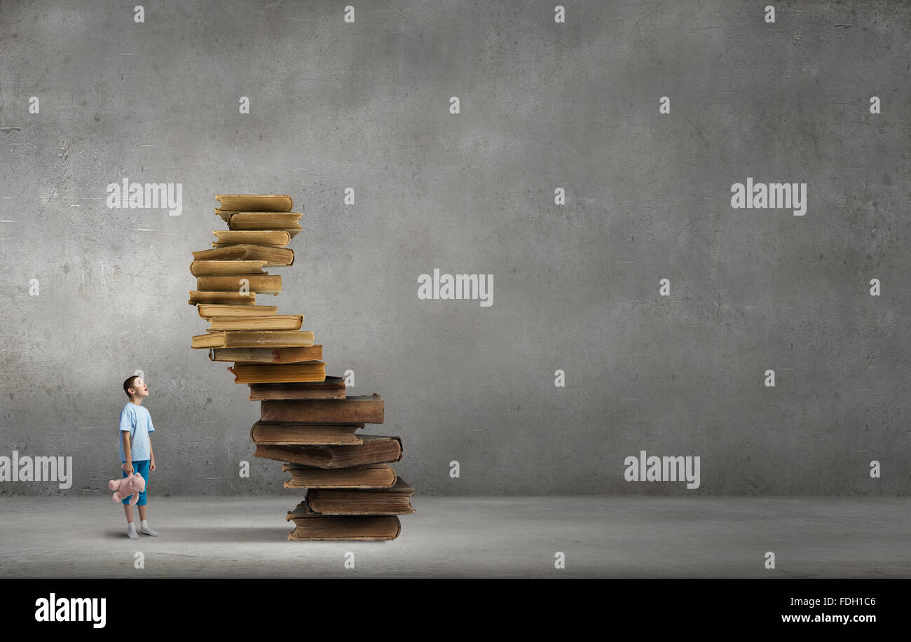Cute little boy with toy bear sitting on pile of books Stock Photo - Alamy