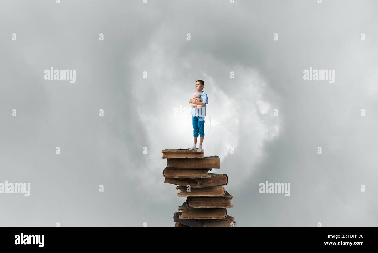 Cute little boy with toy bear standing on pile of books Stock Photo - Alamy