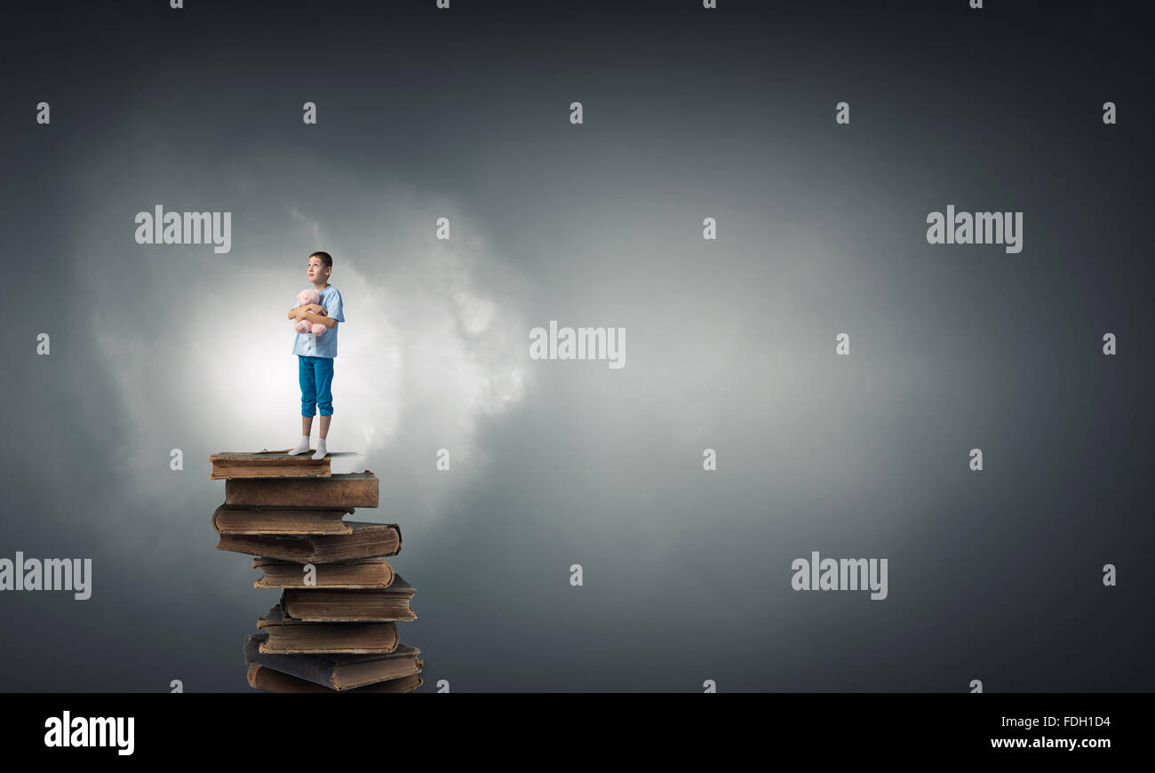 Cute little boy with toy bear standing on pile of books Stock Photo - Alamy