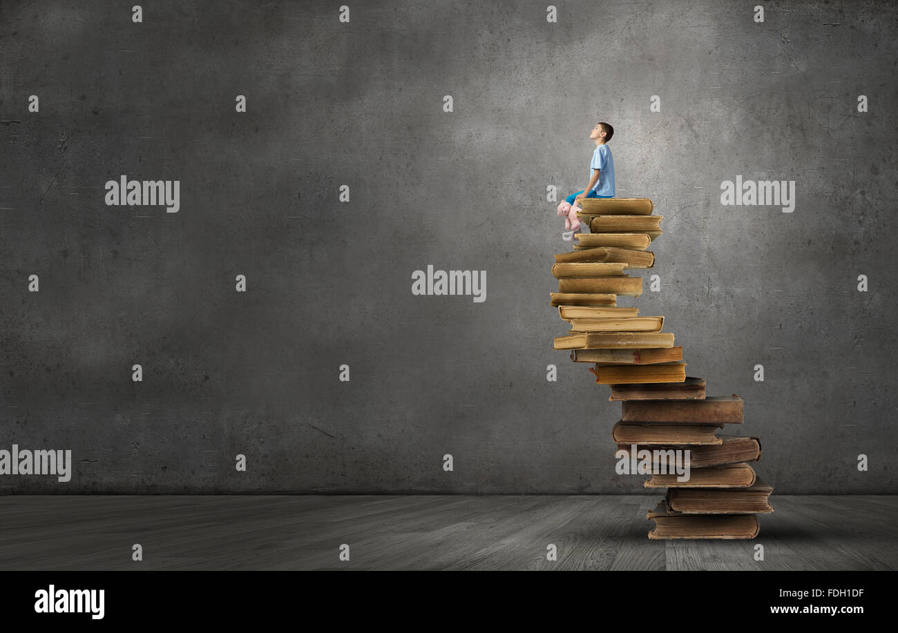 Cute little boy with toy bear sitting on pile of books Stock Photo - Alamy