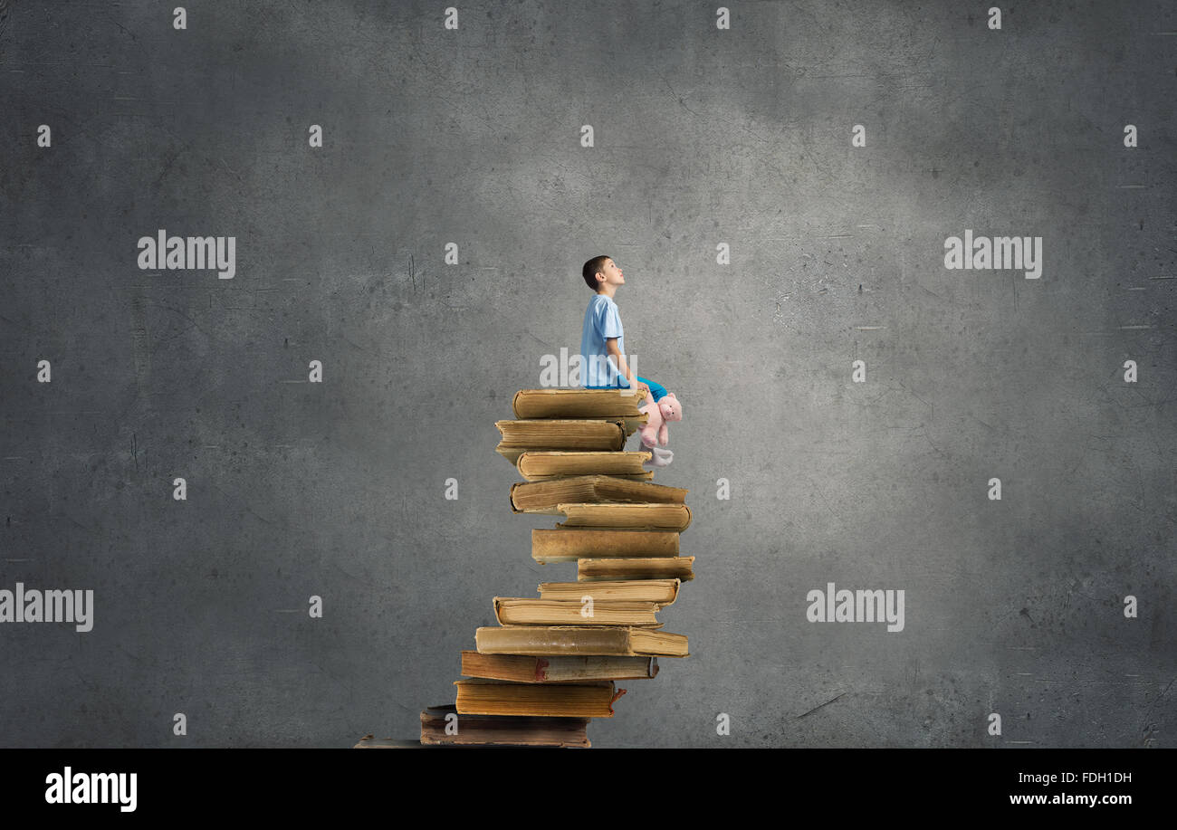 Cute little boy with toy bear sitting on pile of books Stock Photo - Alamy