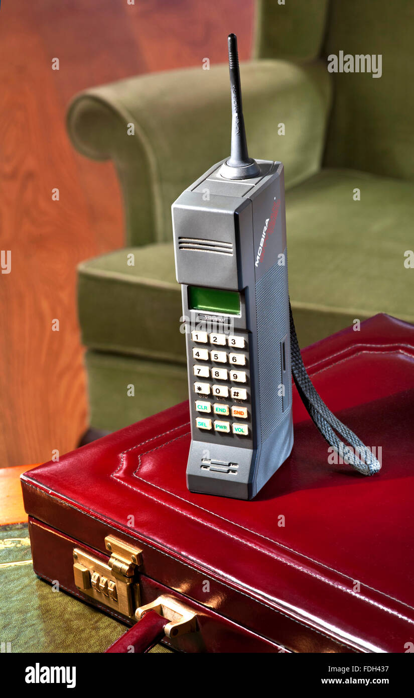 CELL MOBILE MOBIRA CITYMAN 1987 first generation hand held mobile cell phone Mobira Cityman 1320 1980’s Technology style with 80’s briefcase and chair Stock Photo