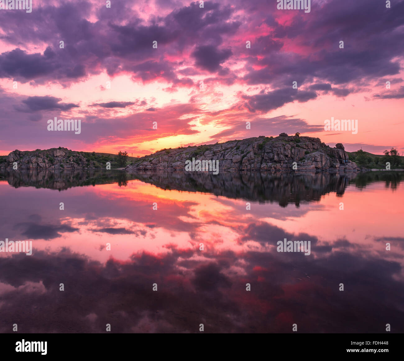 Beautiful landscape. Colorful sunset at the lake with clouds reflected in water. Stock Photo