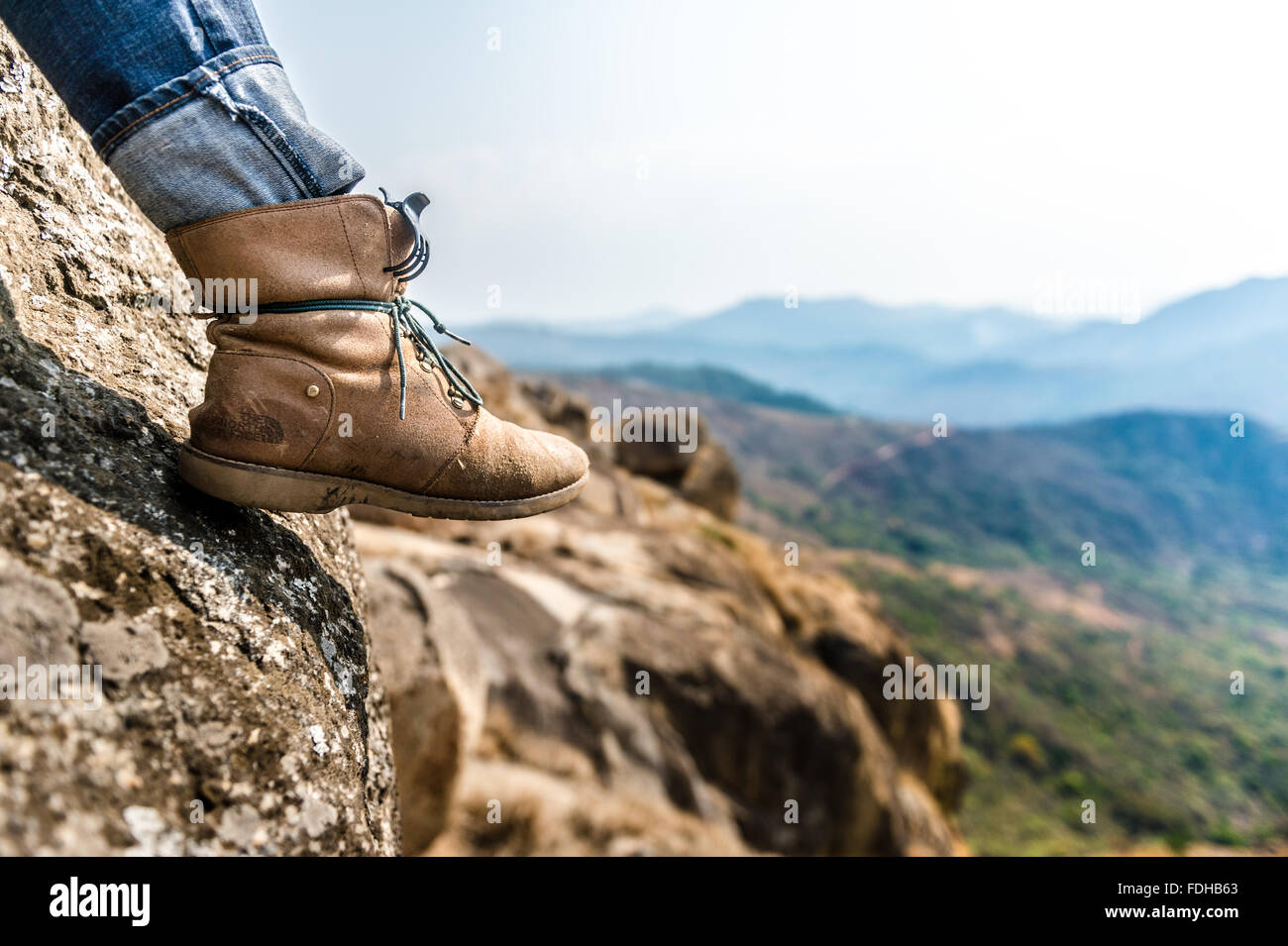 A person's boot hanging over a boulder in the Mlilwane Wildlife Sanctuary in Swaziland, Africa. Stock Photo