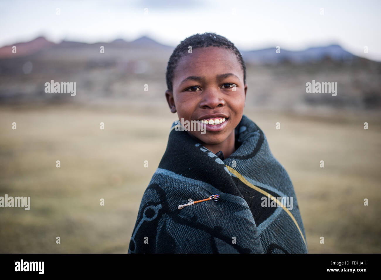 Portrait of a young boy wrapped in a blanket with mountains in the background in Sani Pass, Lesotho, Africa. Stock Photo