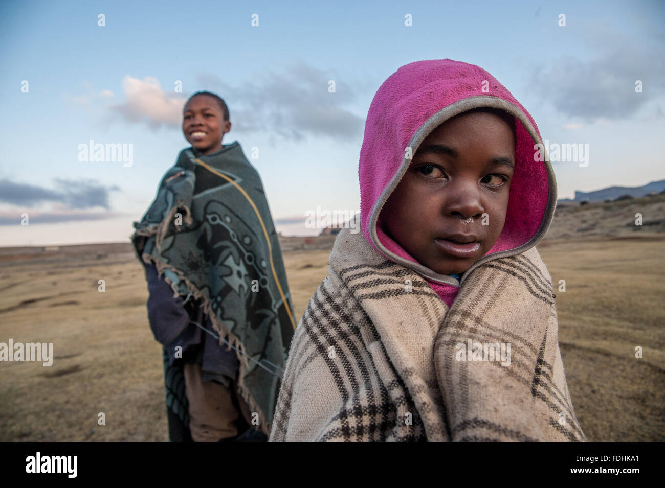 Two children wrapped in blankets in the middle of a vast plane in Sani Pass, Lesotho. Stock Photo