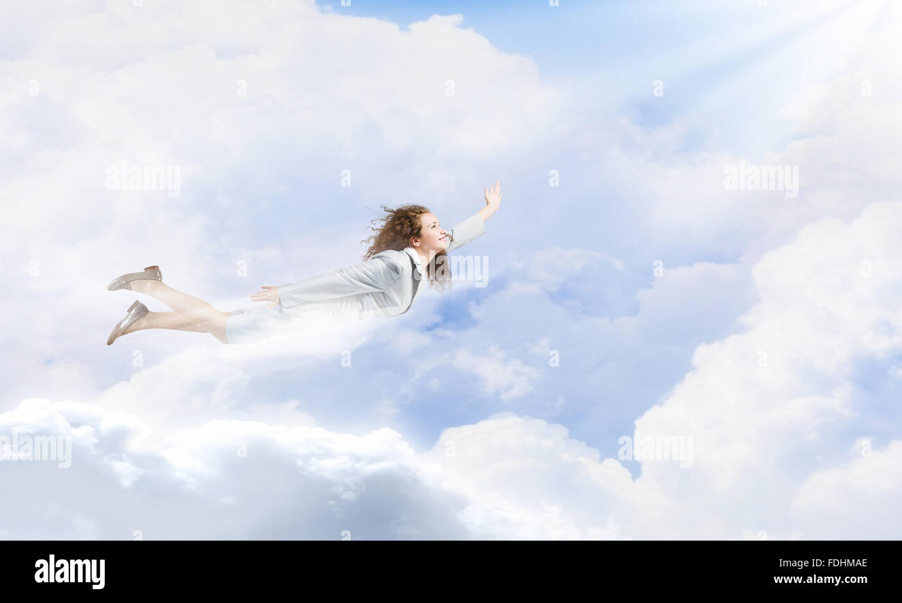 Young pretty businesswoman flying in blue sky Stock Photo