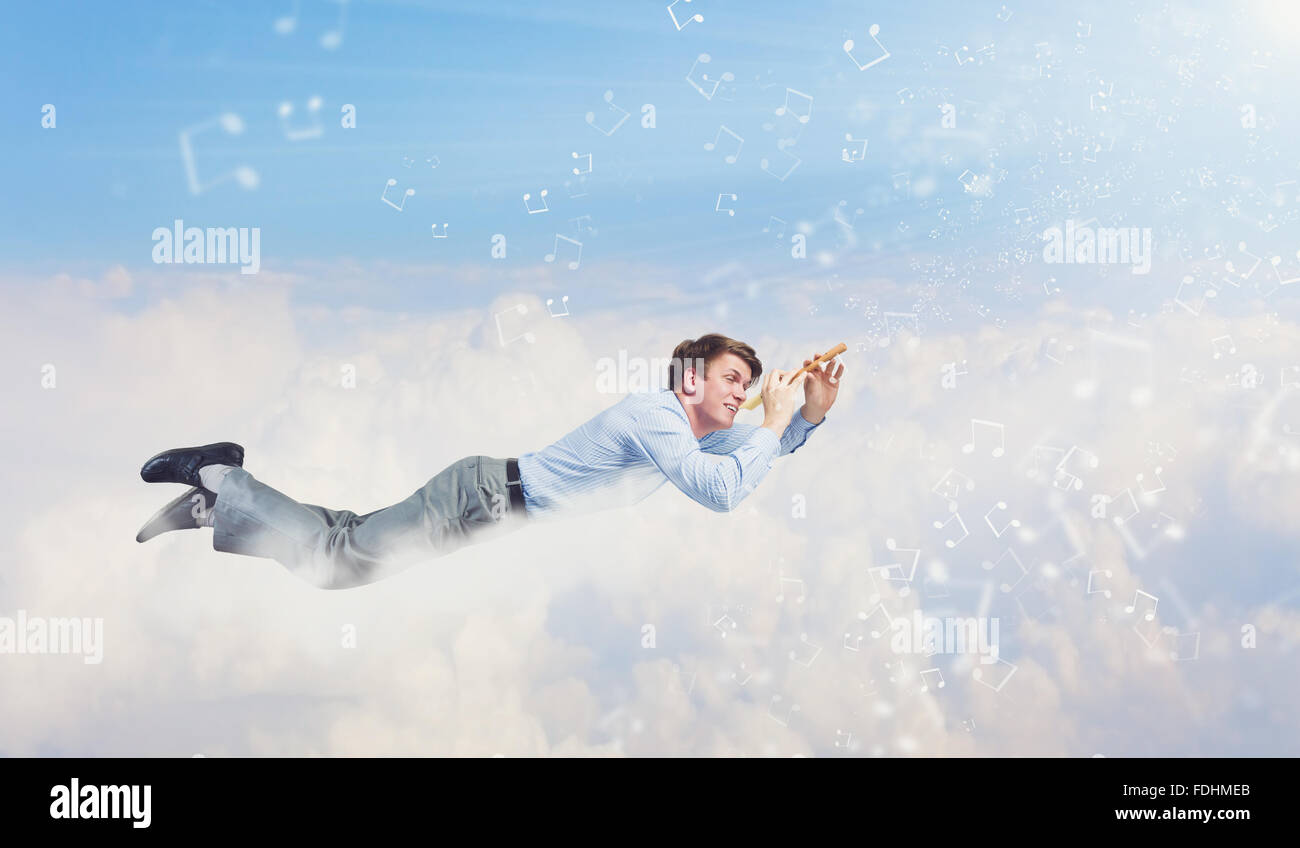 Young businessman flying in sky and playing fife Stock Photo Alamy
