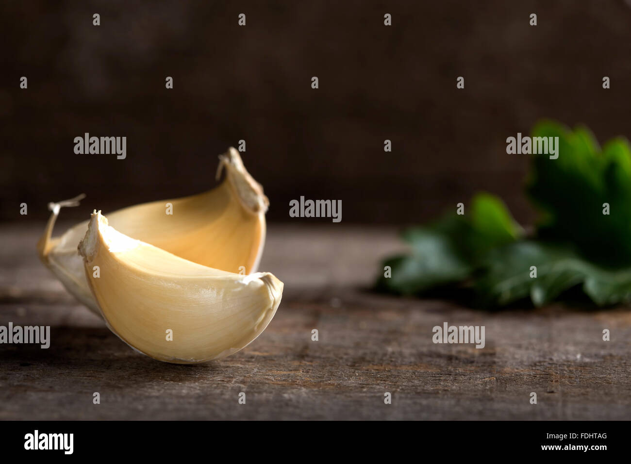 Fresh garlic on wooden table with parsley in background Stock Photo