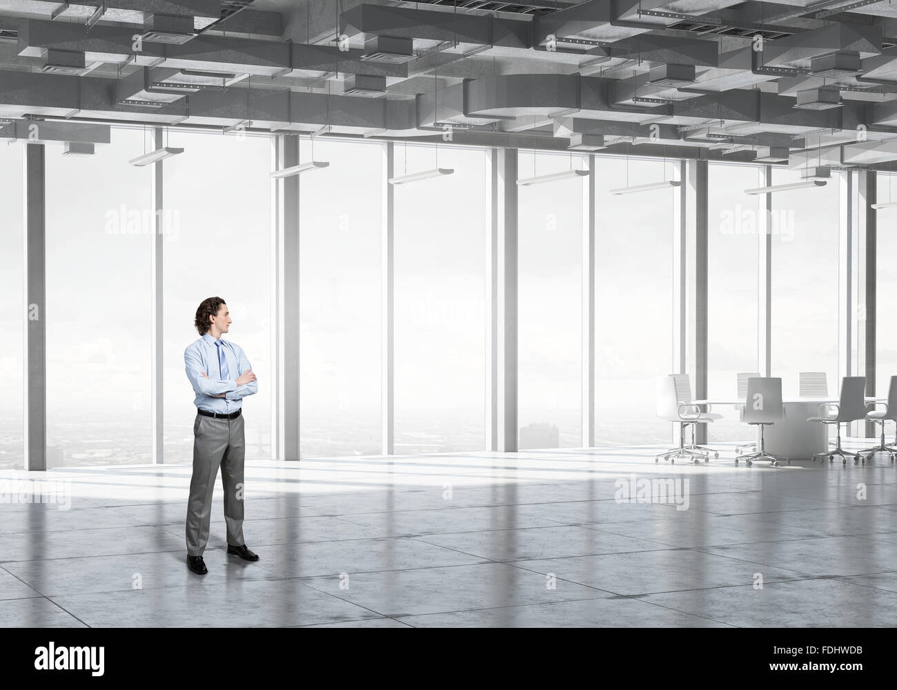 Confident businessman standing with arms crossed on chest in modern ...