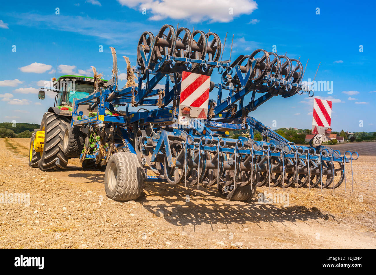 John Deere 8310R farm tractor and Kockering Quadro rotary tiller cultivator - France. Stock Photo