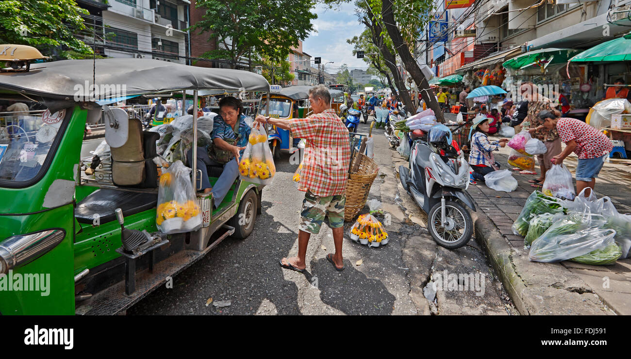 Vendor helping customer with her shopping bags at Pak Khlong Talat flower market. Bangkok, Thailand. Stock Photo