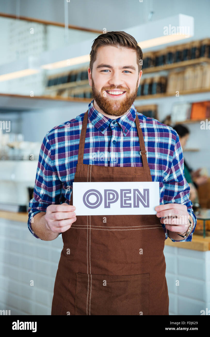 Cheerful handsome cafeteria worker in checkered shirt and brown apron