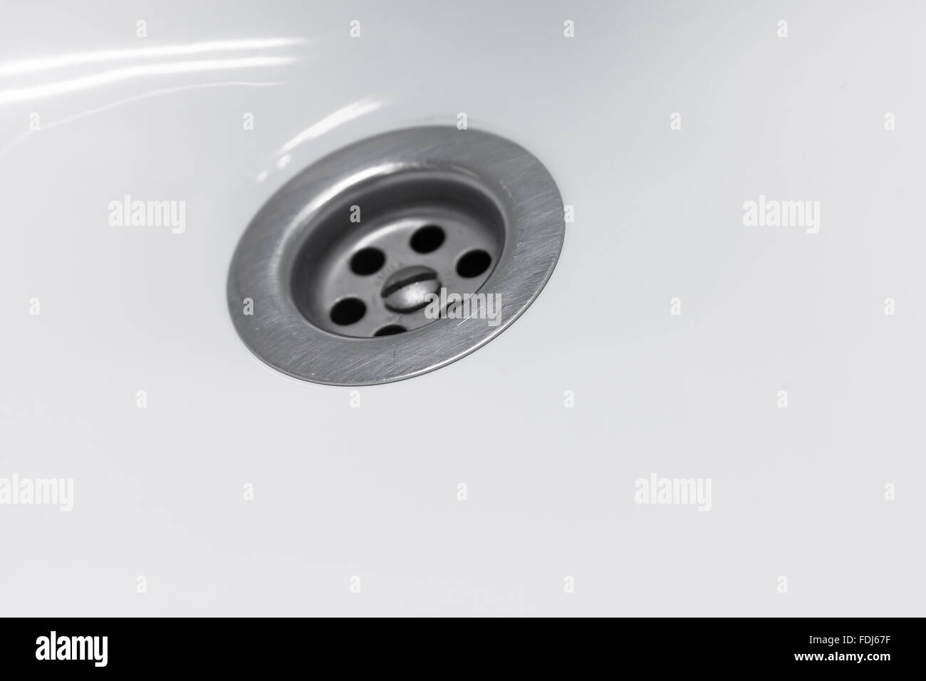 Standard round drain hole in white domestic sink, macro photo with selective focus Stock Photo