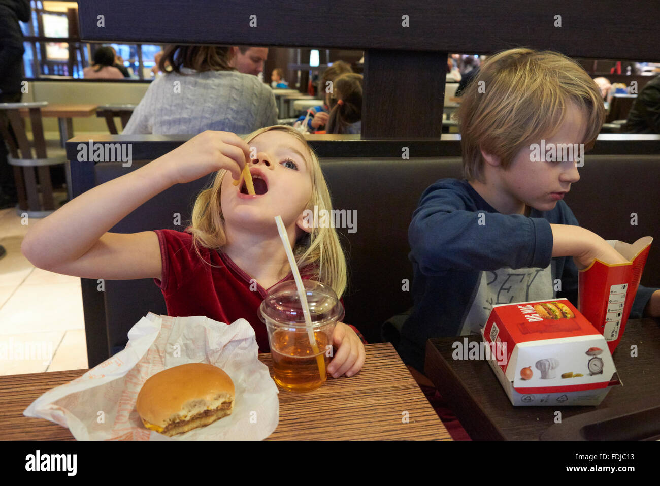 Siblings, brother and sister eating in fast food restaurant Stock Photo